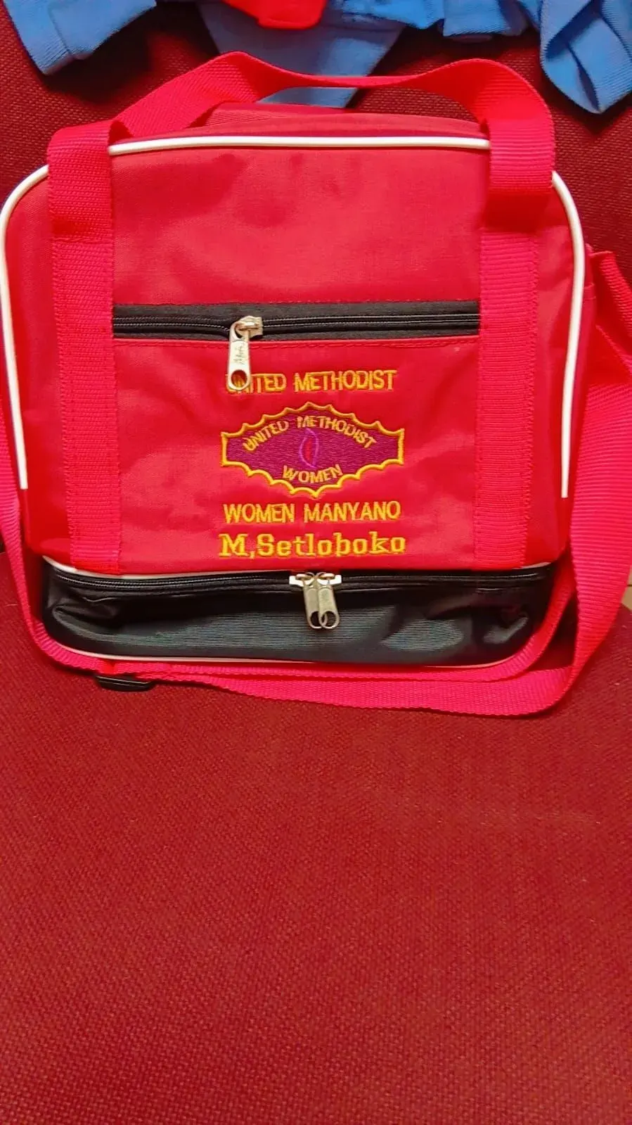 Red cooler bag embroidered with a church logo and personal name by Nosibele