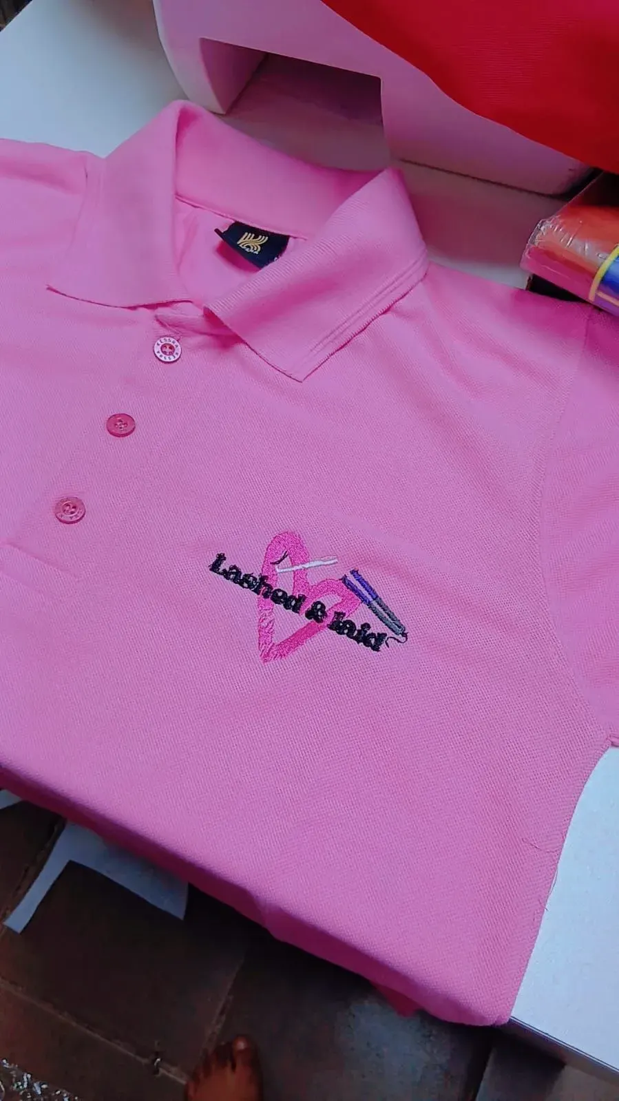 Pink golf shirt with embroidered Lashed & Laid salon logo
