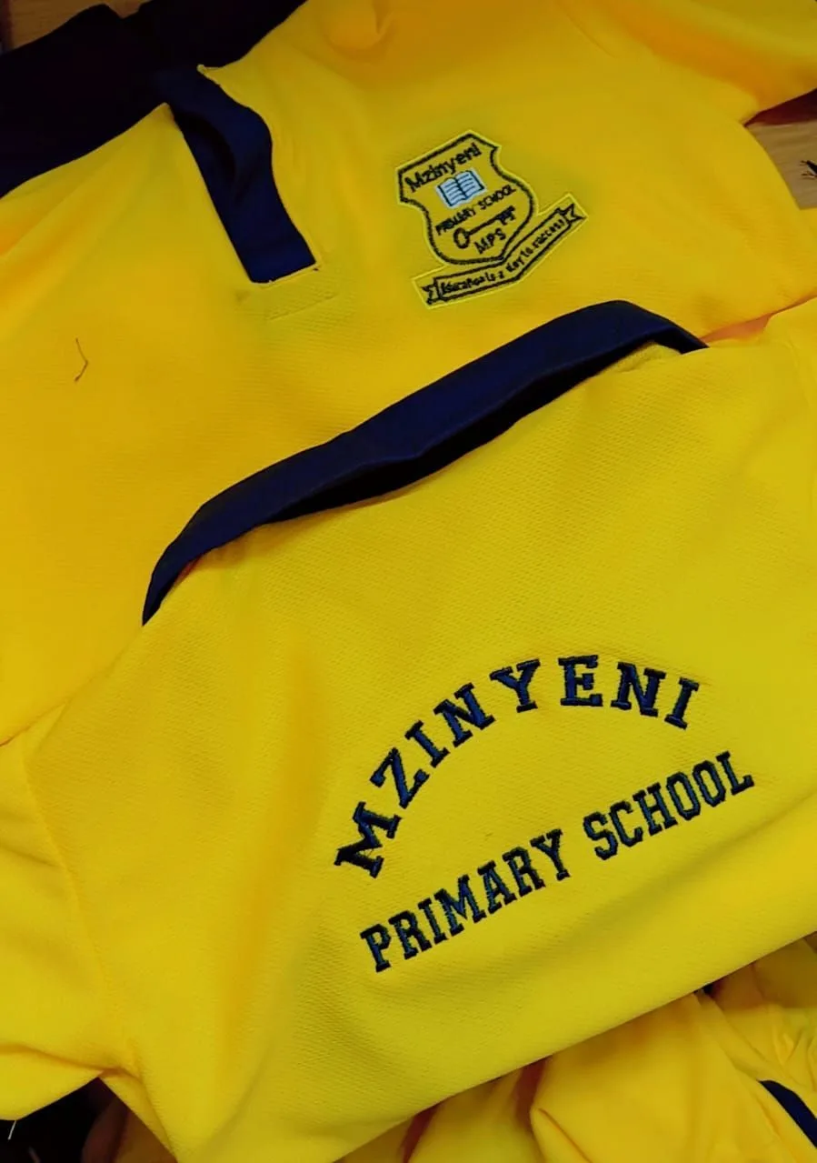Yellow Mzinyeni Primary School shirts with embroidered crest and lettering